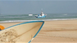 Garde à vue pour le bateau pêchant au milieu des surfeurs